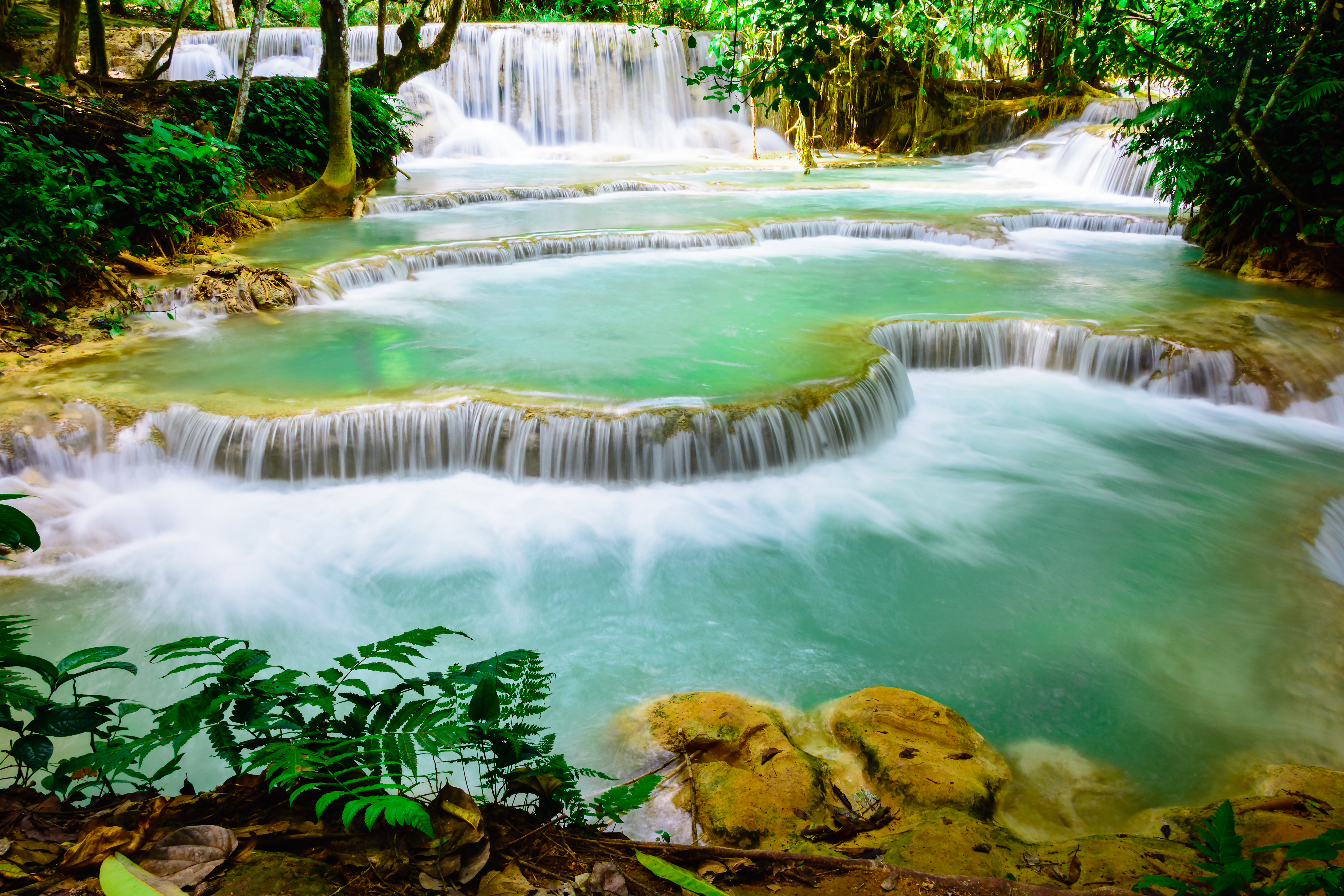 Kuang Si Waterfalls' cascading white foam over multiple rock tiers.