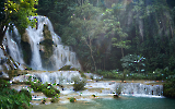 Kuang Si Waterfalls illuminated by sunlight, creating a sparkling effect on the water.