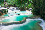 A narrow forest path leading to a hidden view of Kuang Si Waterfalls.