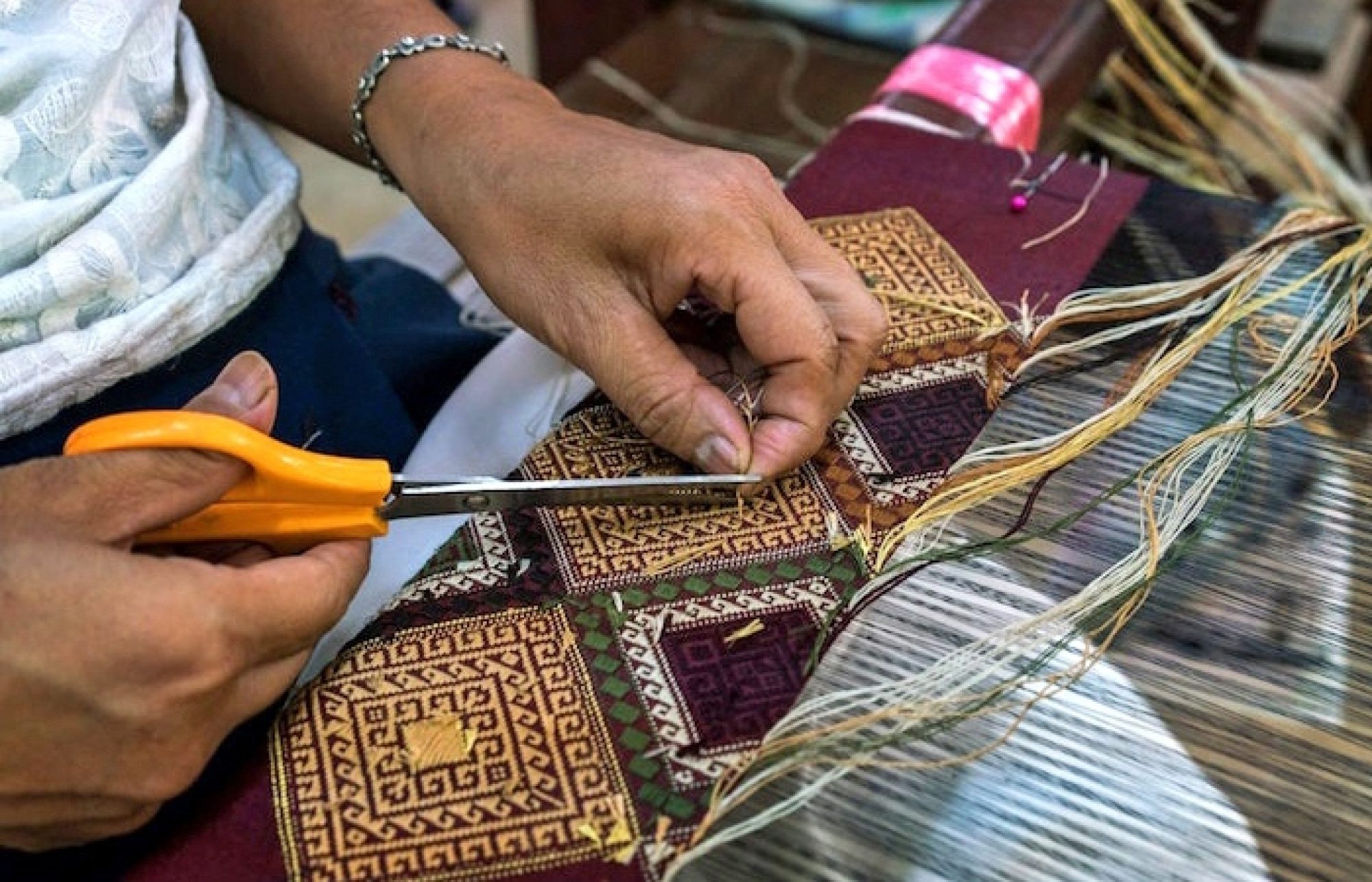 A Lao artisan weaving intricate patterns on a traditional loom.