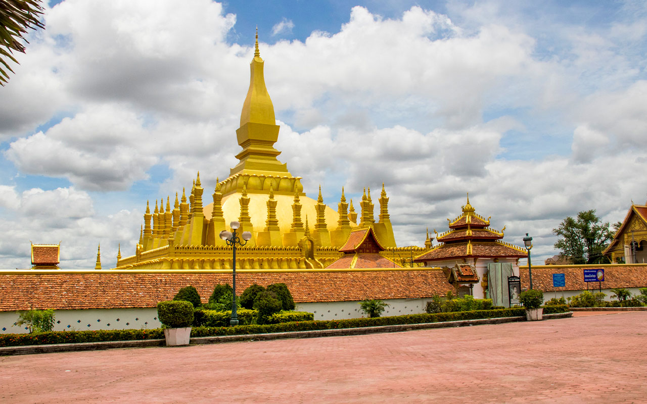 The golden That Luang Stupa in Vientiane, Laos, under a clear blue sky.