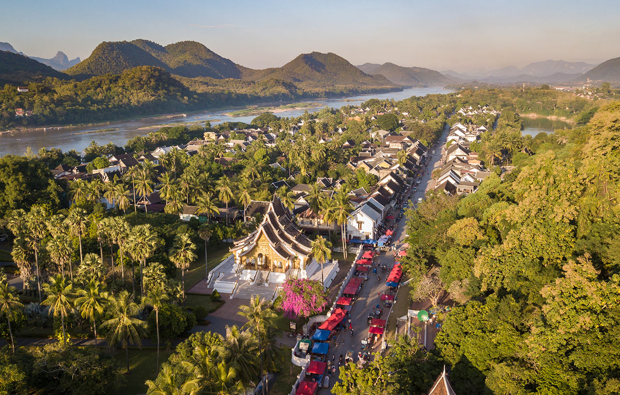 Panoramic view of Luang Prabang at sunrise, showing the town, Mekong River, and mountains shrouded in mist, Laos.