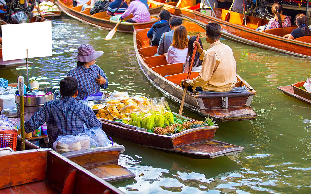 Vibrant floating market in Thailand with vendors selling fresh produce and goods from boats on a canal