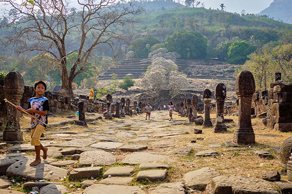 Stone ruins of a temple complex on a hillside, with intricate carvings visible, Wat Phou, Laos.