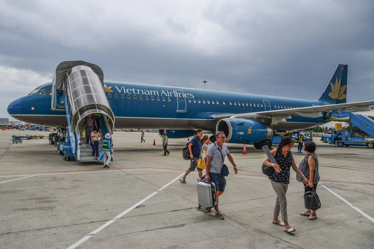 Passengers with luggage stepping off a Vietnam Airlines plane onto the airport apron