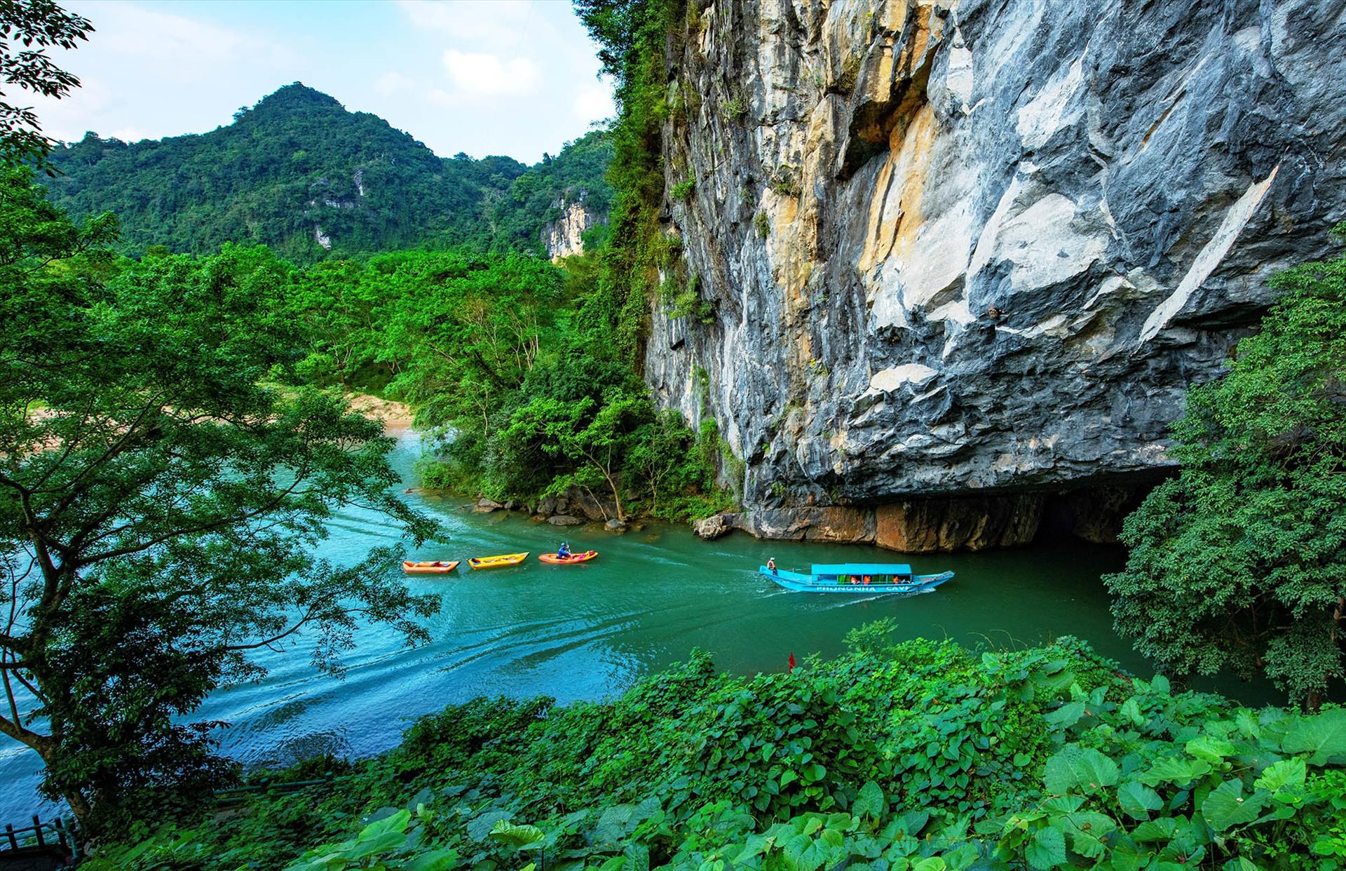 Tourist boat and kayaks on a turquoise river at the Phong Nha Cave entrance in Quang Binh, Vietnam